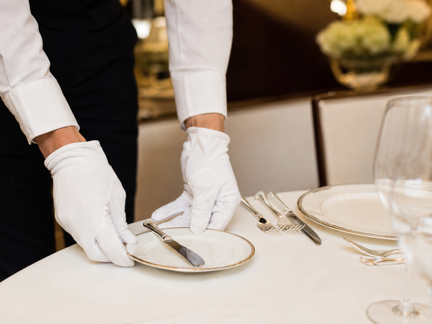 Besteck wird fachgerecht an einem Restauranttisch eingedeckt