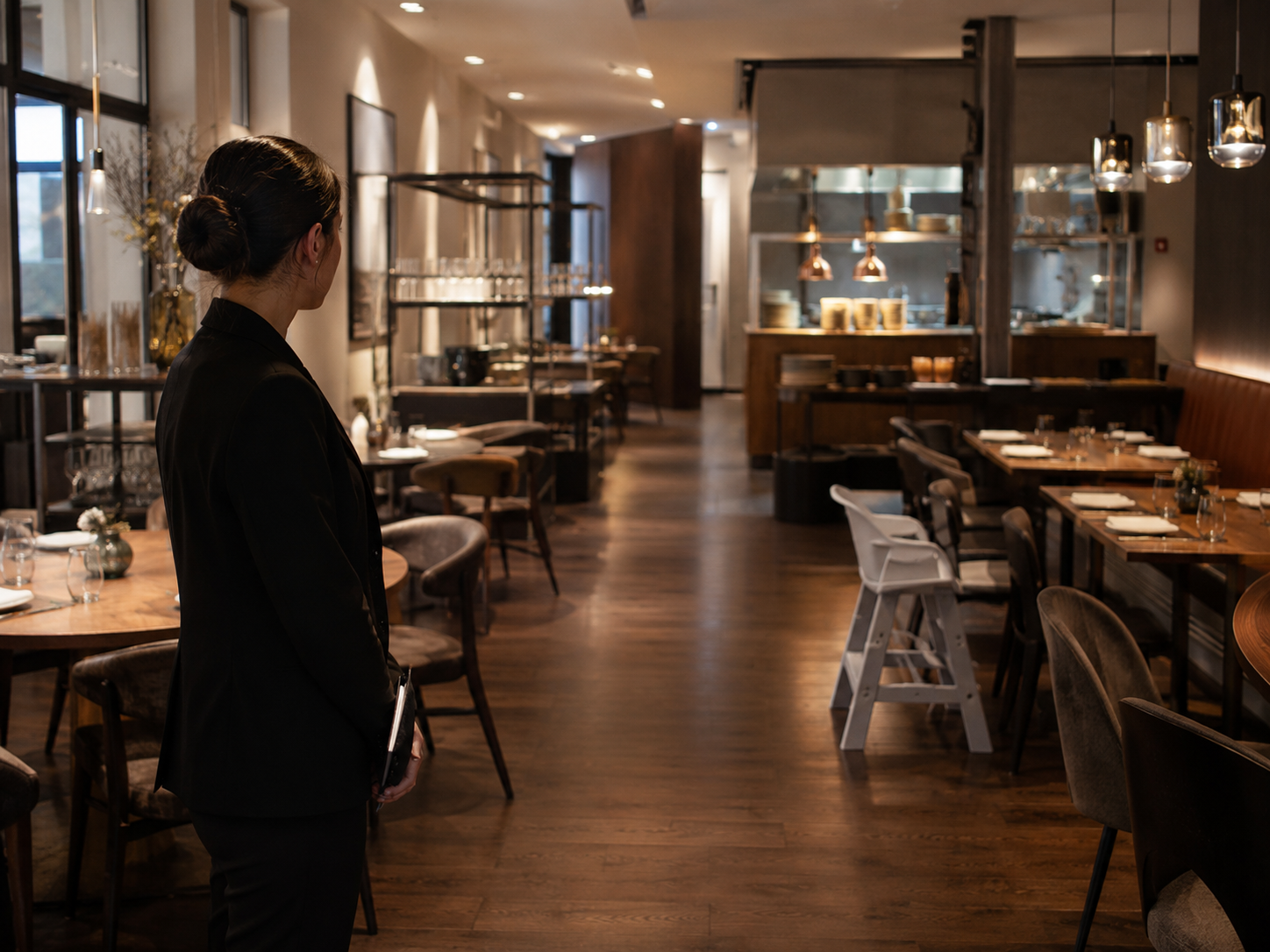 Restaurantleiterin kontrolliert vor der Öffnung Gastraum, Laufwege und vorbereitete Kinderstühle
