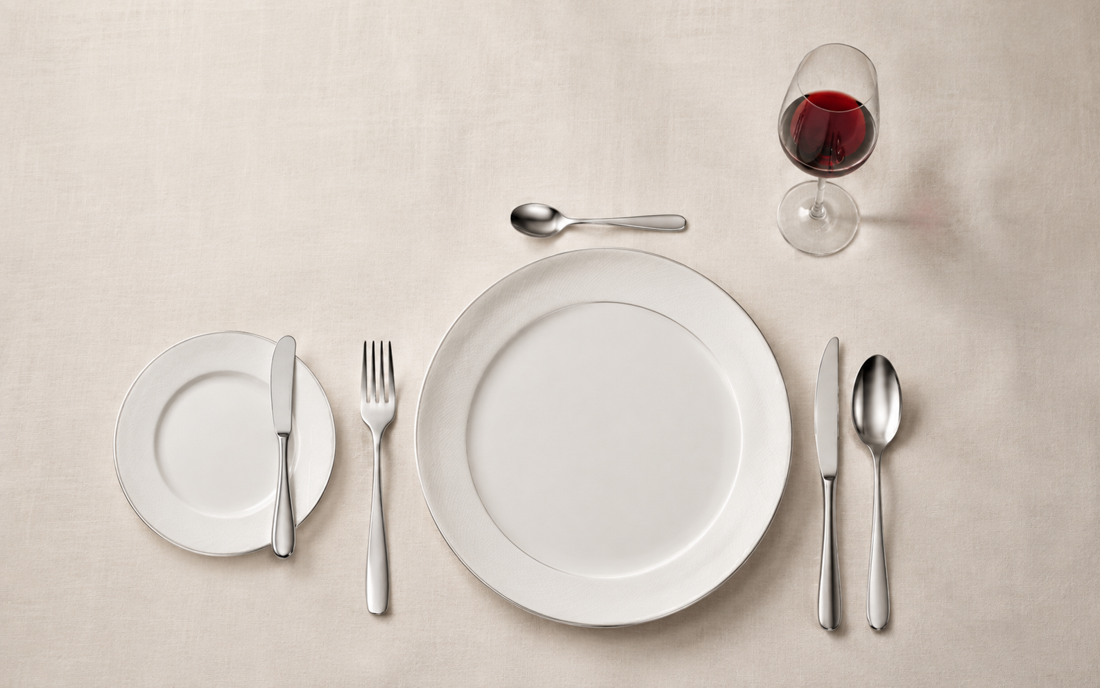 Einfaches Restaurantgedeck mit Teller, Besteck, Brotteller und Glas
