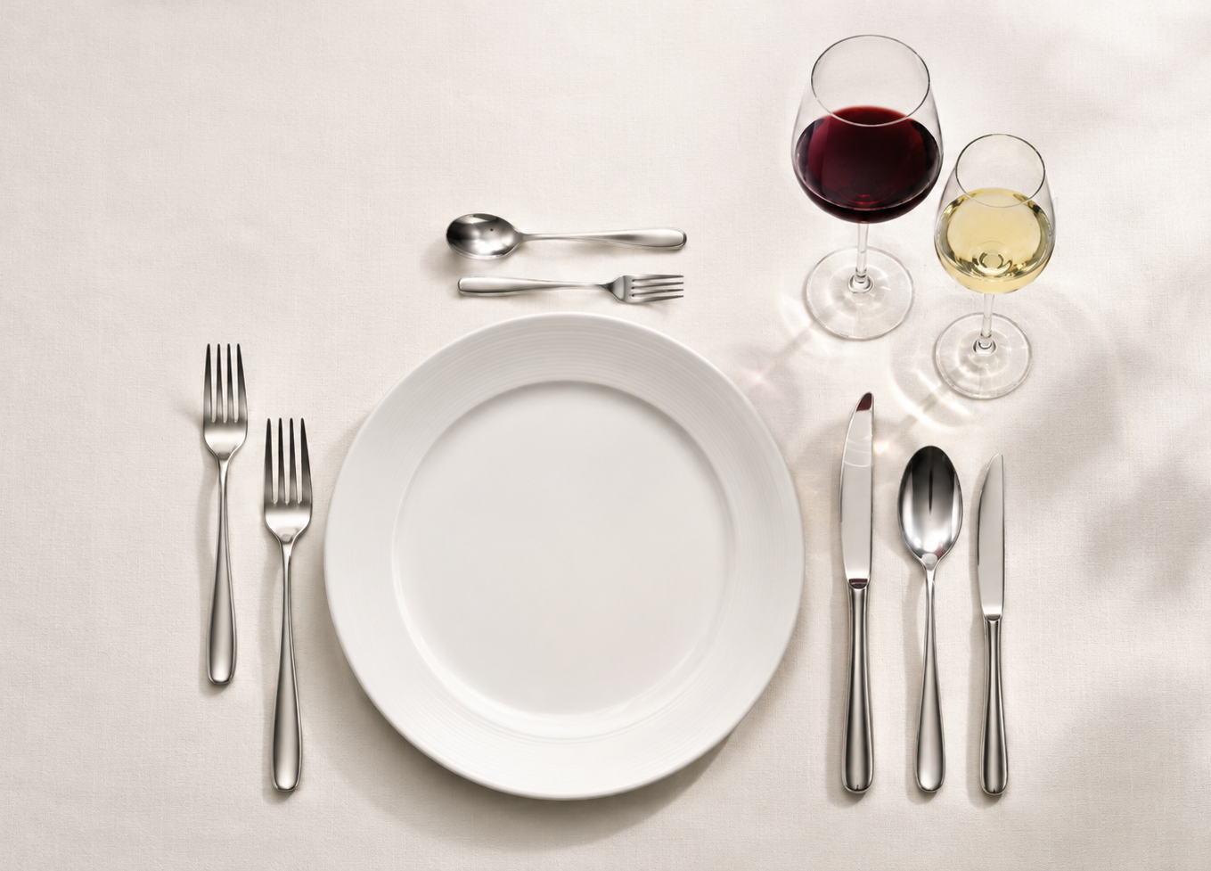 Erweitertes Restaurantgedeck mit mehreren Besteckteilen und Weingläsern